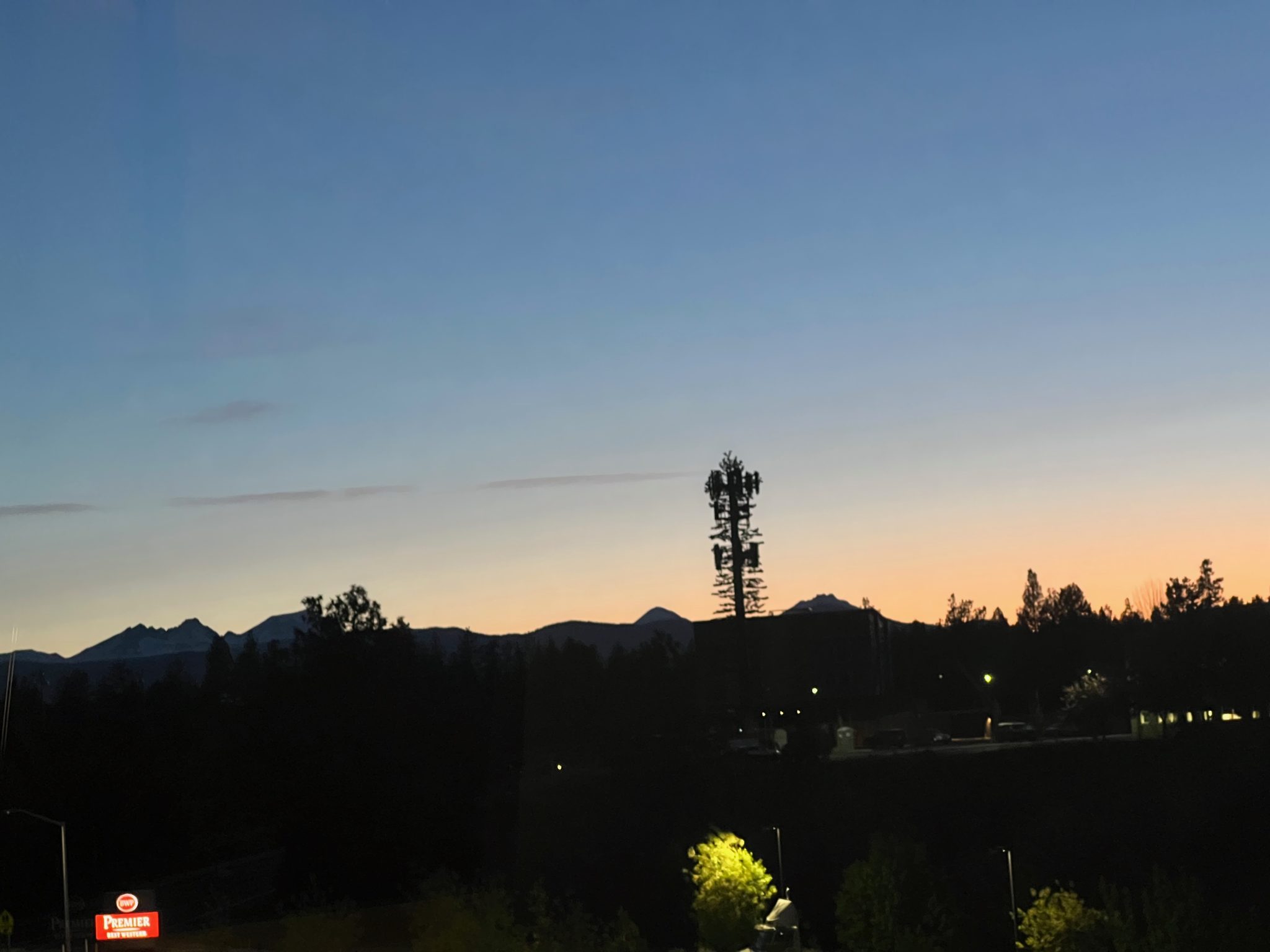 Cascade peaks silhouetted at sunset, a tree-disguised cell tower on the ridgeline