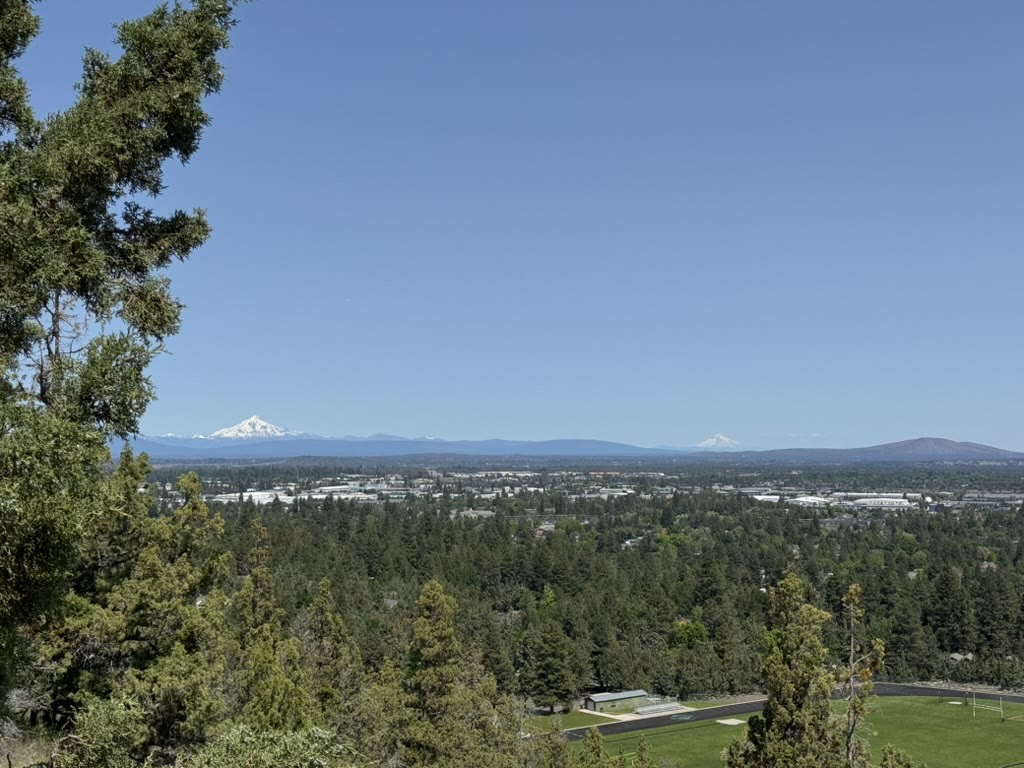 Wide horizon view from Pilot Butte showing the Cascades on both sides with the high desert and town in between