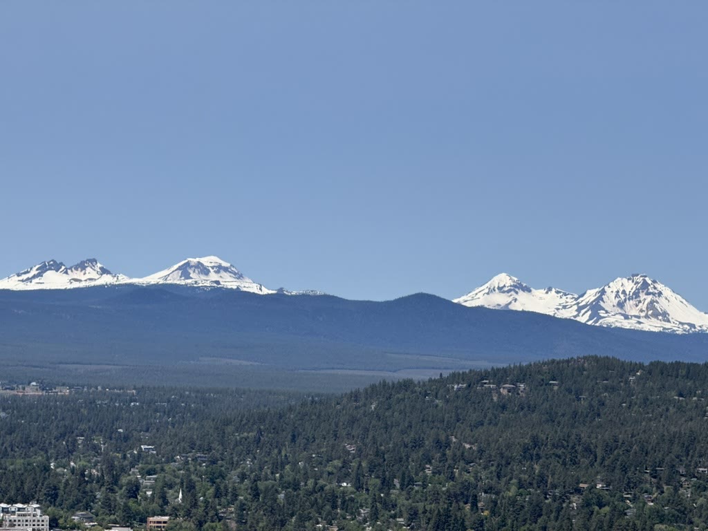 Sister Mountains rising above the high desert, snow on the peaks, pines in the foreground