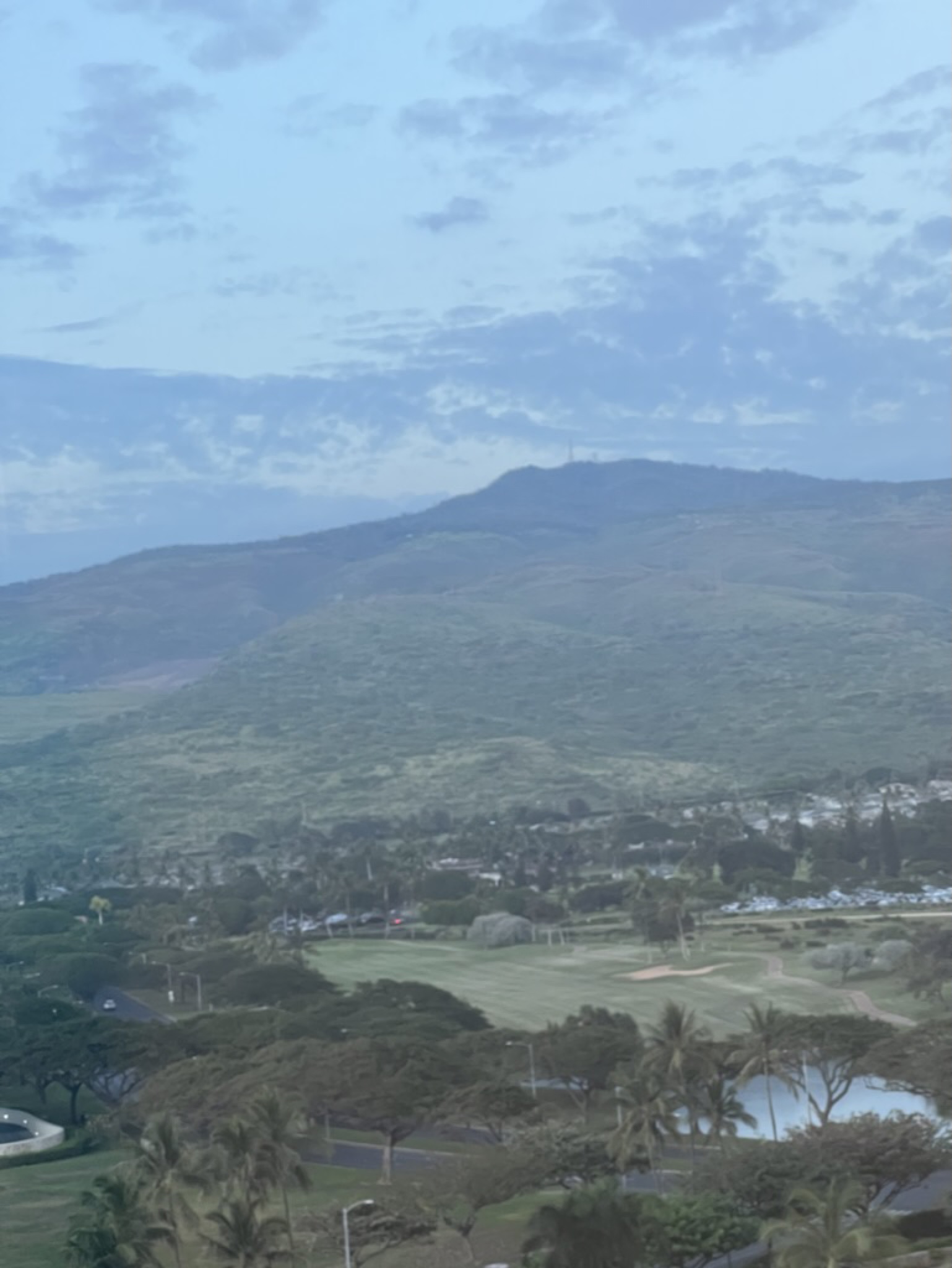 The view east from the resort — golf course, palms, and the Wai'anae Range rising in the haze