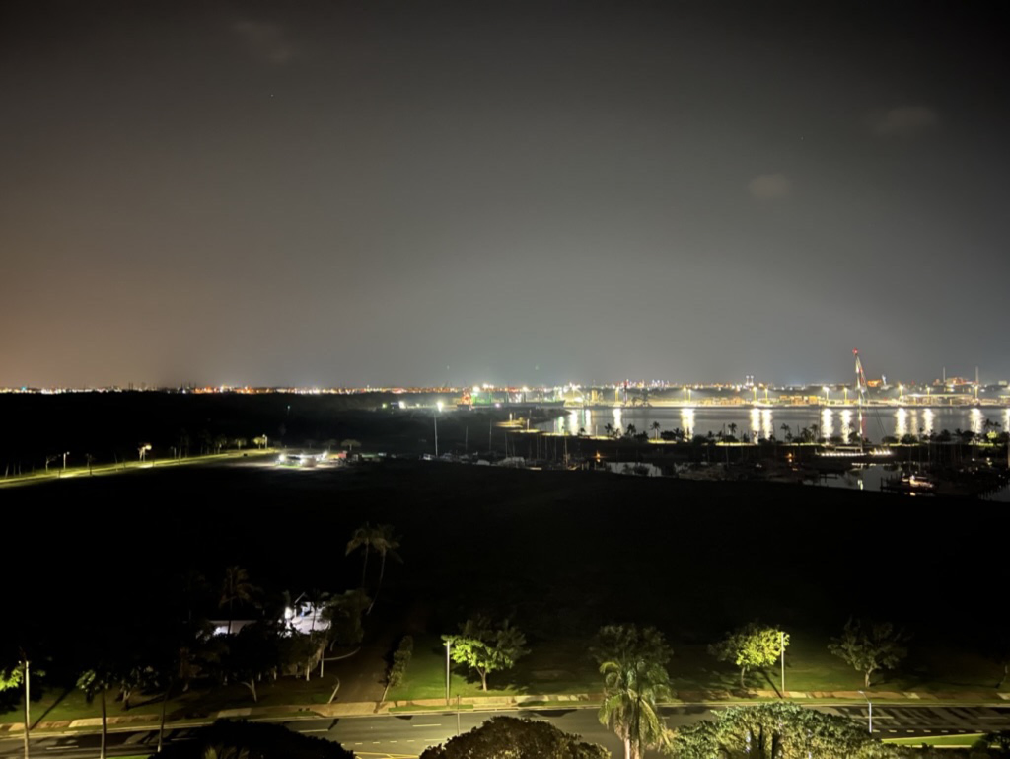 View from the Ko Olina room at night — distant harbor lights stretched across the dark, the resort grounds and palms in the foreground