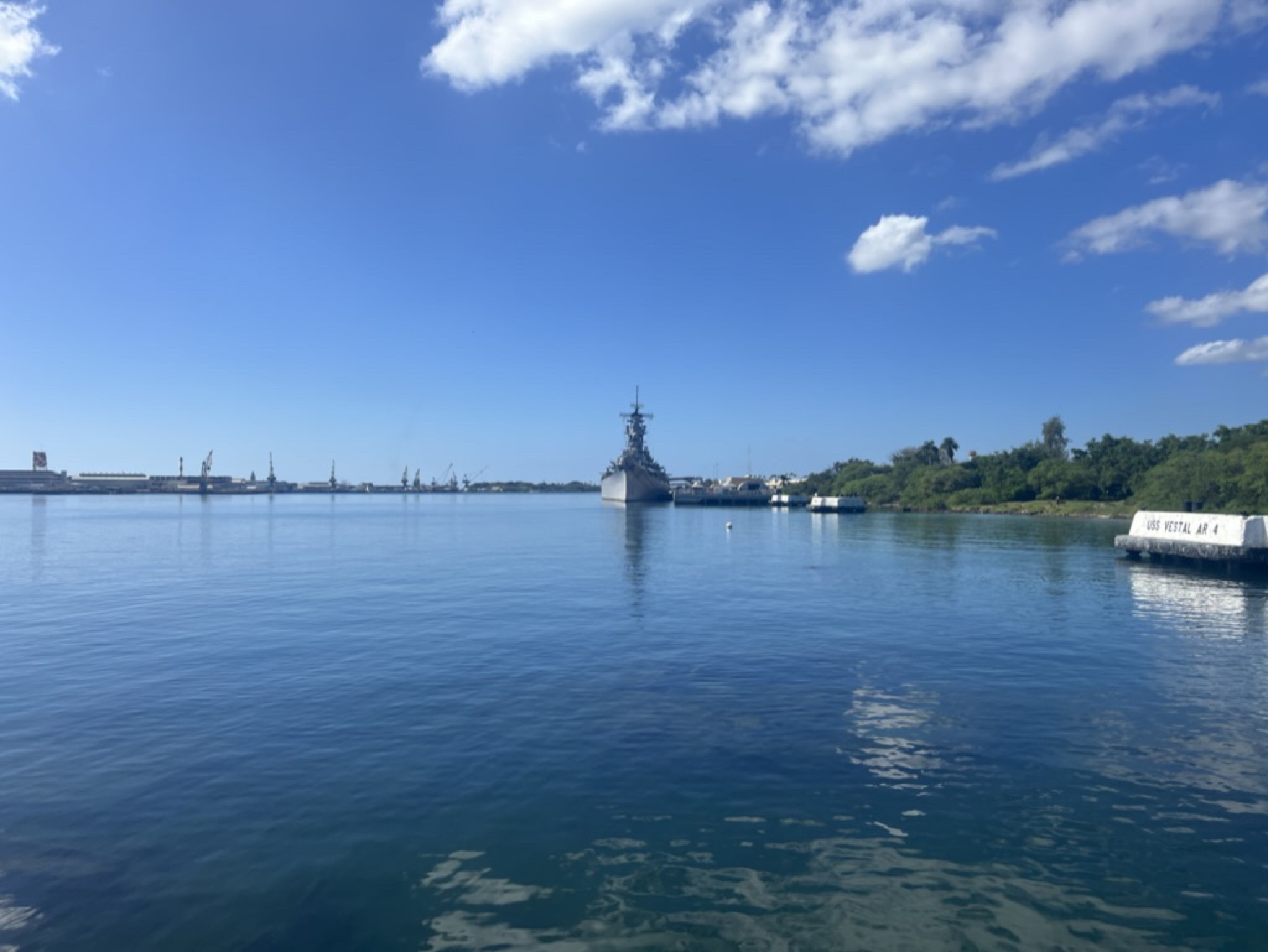 The USS Missouri docked at the end of the channel, palms and harbor calm in the foreground