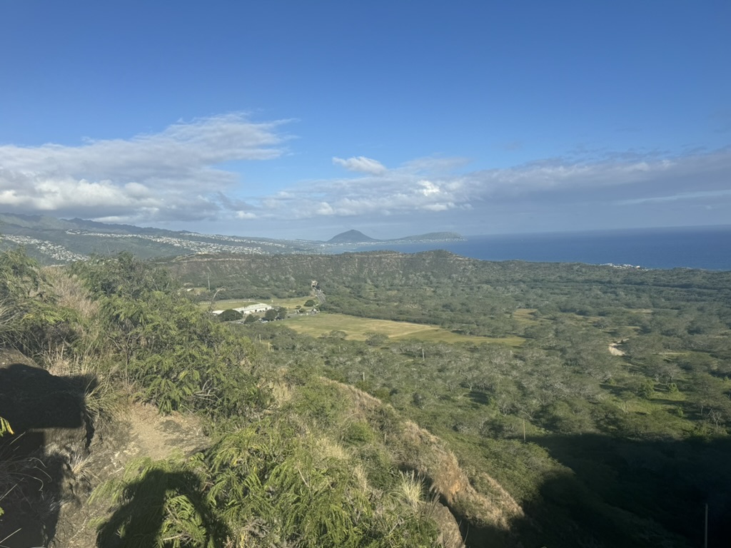 A single fluffy cumulus cloud above the Mokulua Islands with a swimmer crossing the foreground