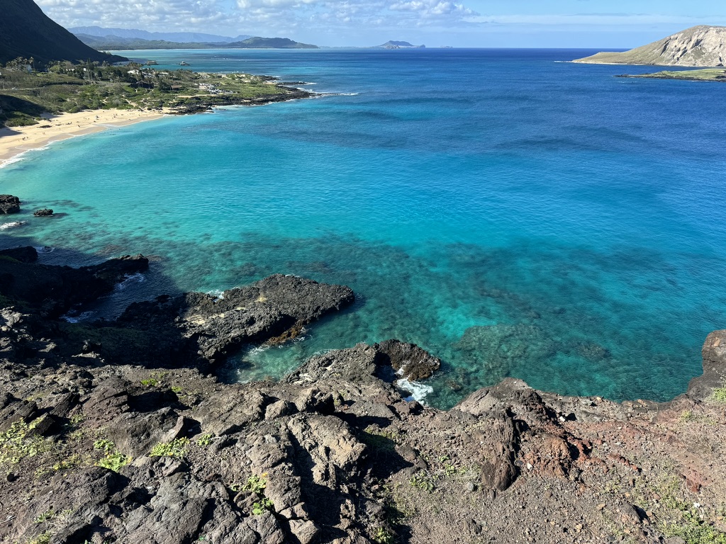 Emerald-green shallows over reef at Makapuʻu, black volcanic rocks in the foreground