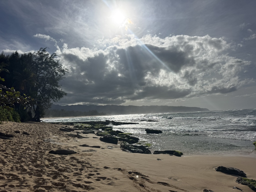 Sun rays through clouds over the surf