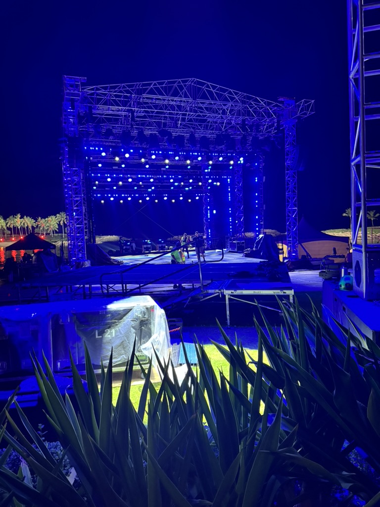Wider view of the same stage from the gardens behind, blue spots washing the rig