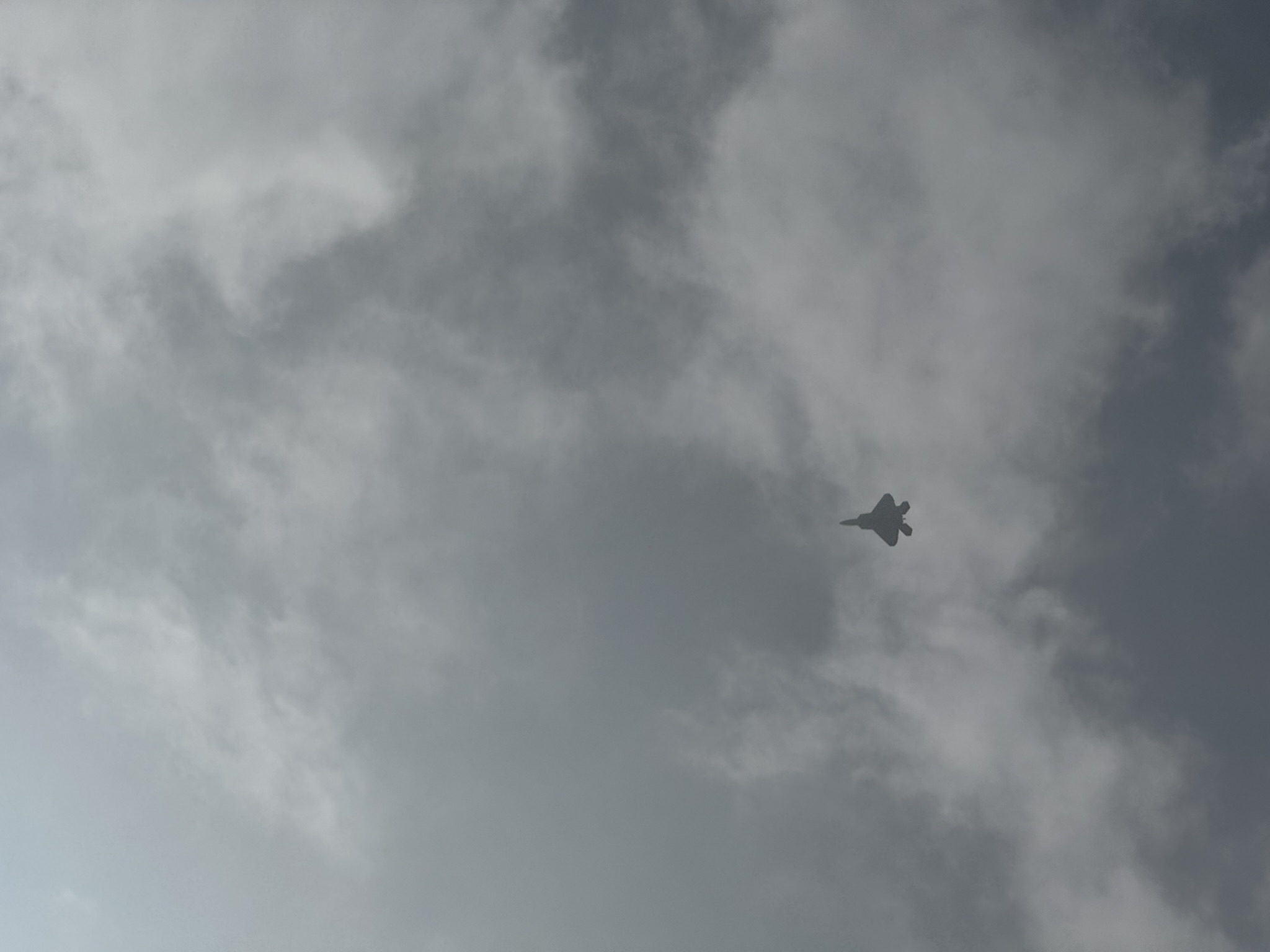 A Lockheed Martin F-22 Raptor through cloud cover overhead