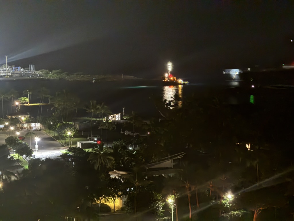 The same marina at night — a single lit vessel out on the dark water