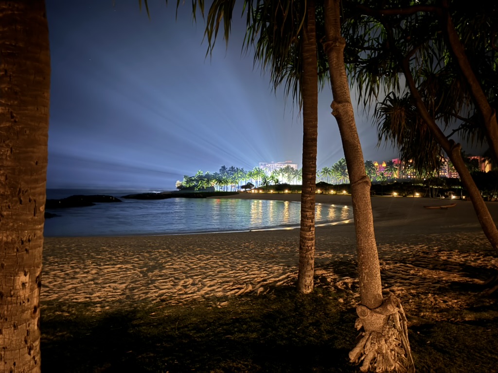 The Ko Olina lagoon at full dark, palm trees lit from below, set lights across the water