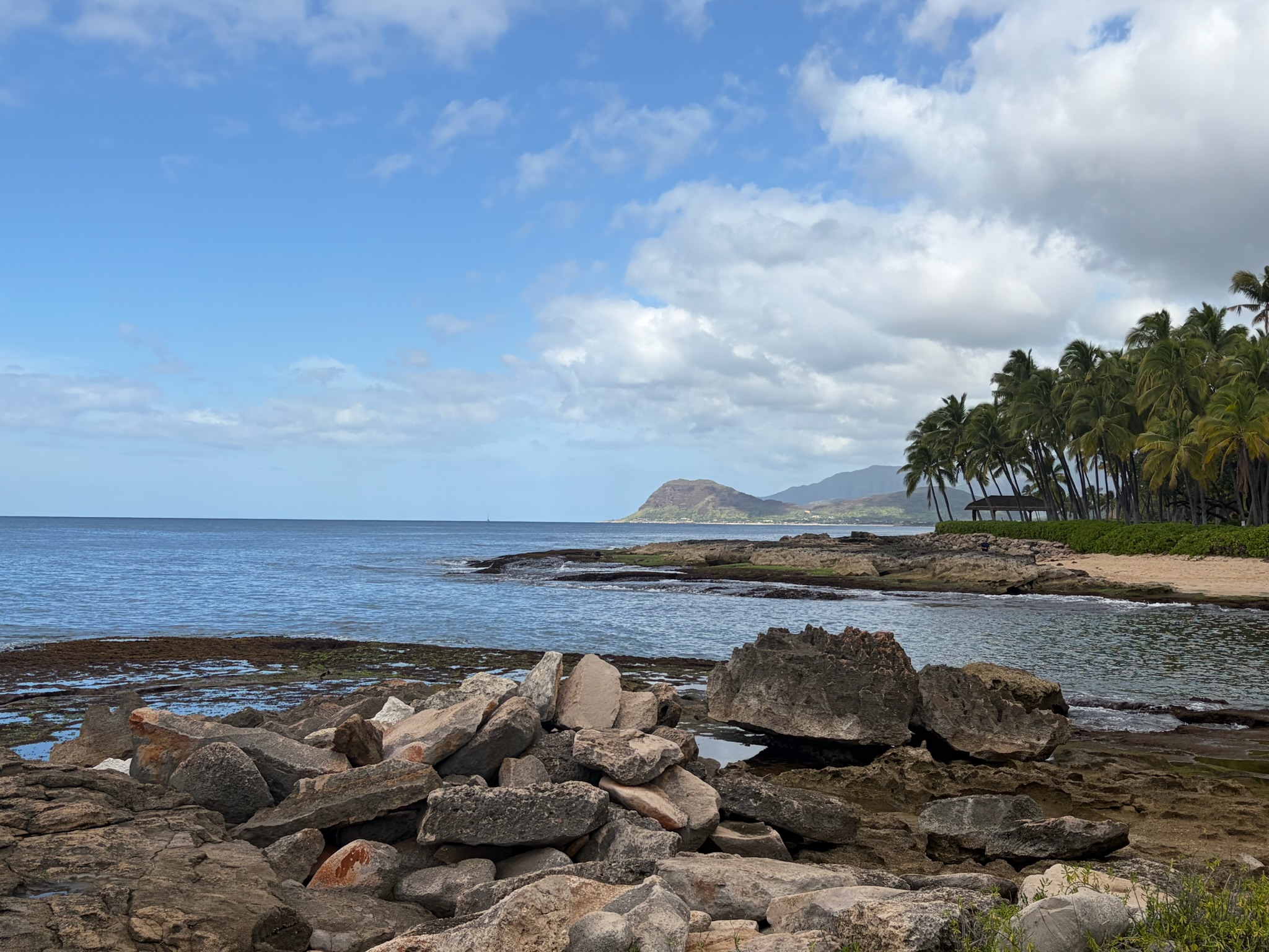 Leeward Oahu coast — rocky tide pools in the foreground, the mountain rising on the right