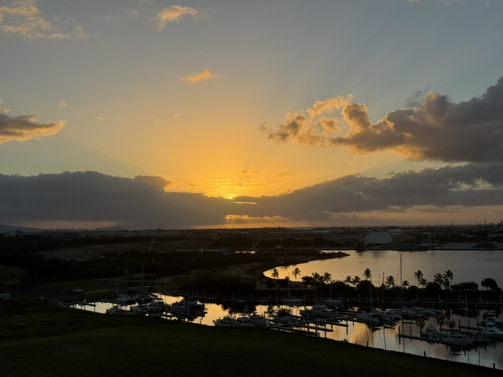 Sun visible at the horizon over the marina, water gone to gold