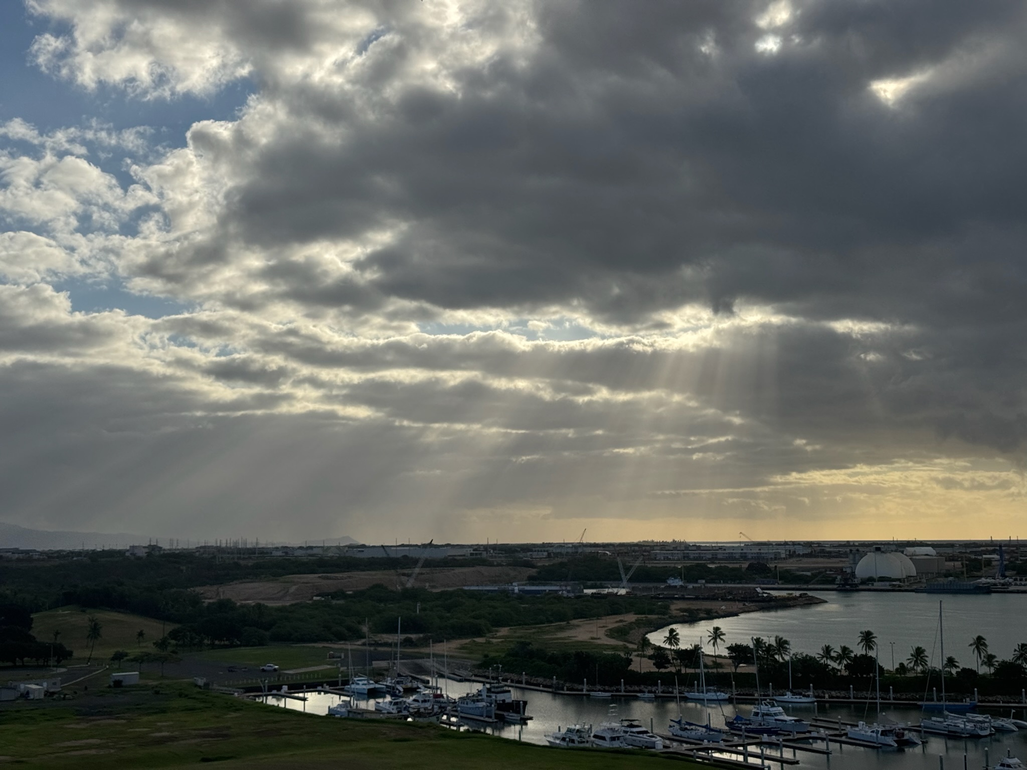 Crepuscular rays piercing the morning cloud deck above the same marina