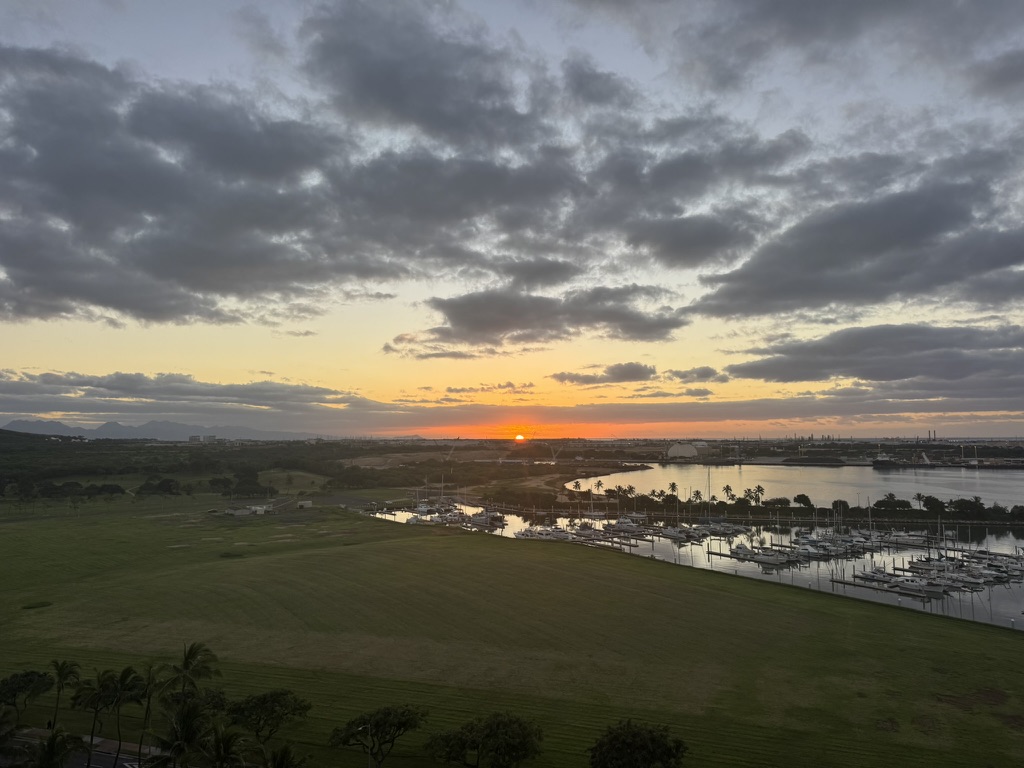 Wider sunset over the marina with the dome of a distant landmark on the horizon