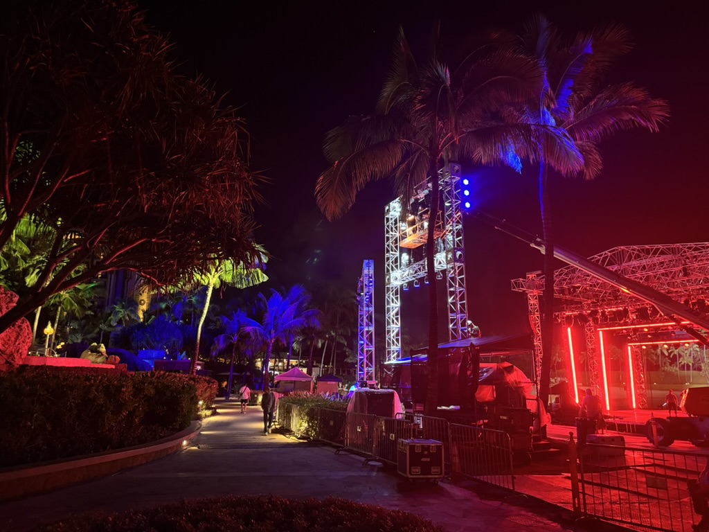 The lit stage at night, blue and red production wash, palms in silhouette