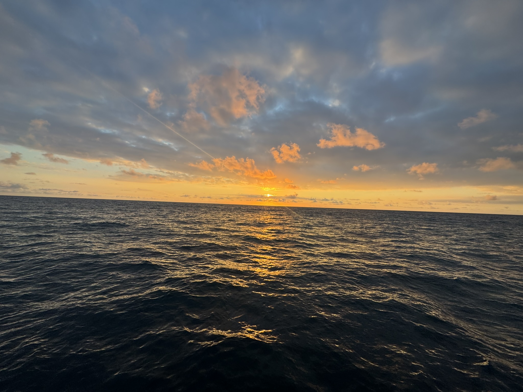 Cloud streaks above a soft ocean sunset