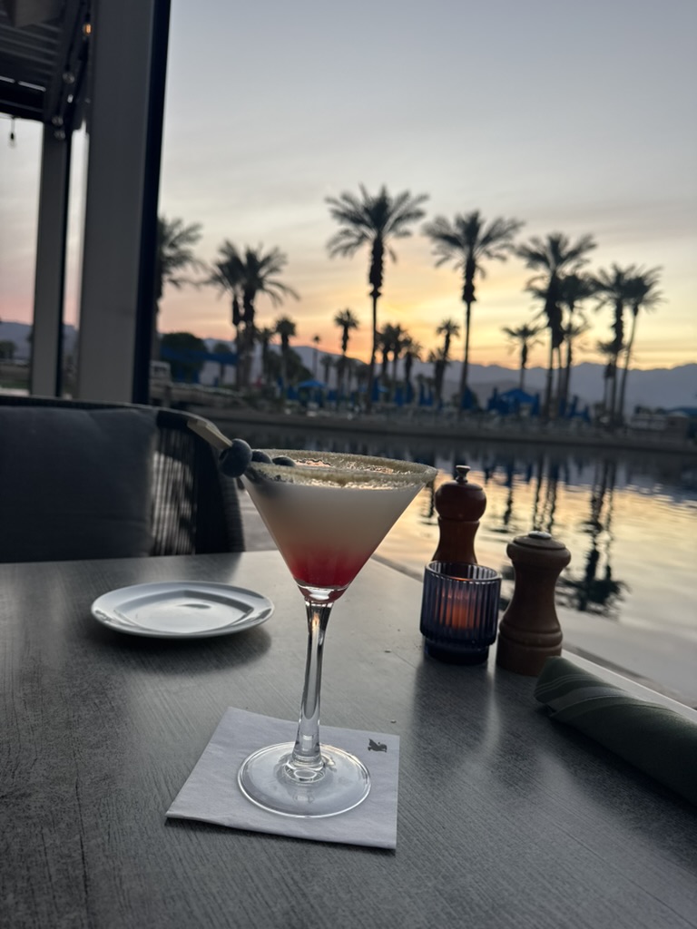 Pomegranate martini at the resort restaurant with a palm-lined sunset behind