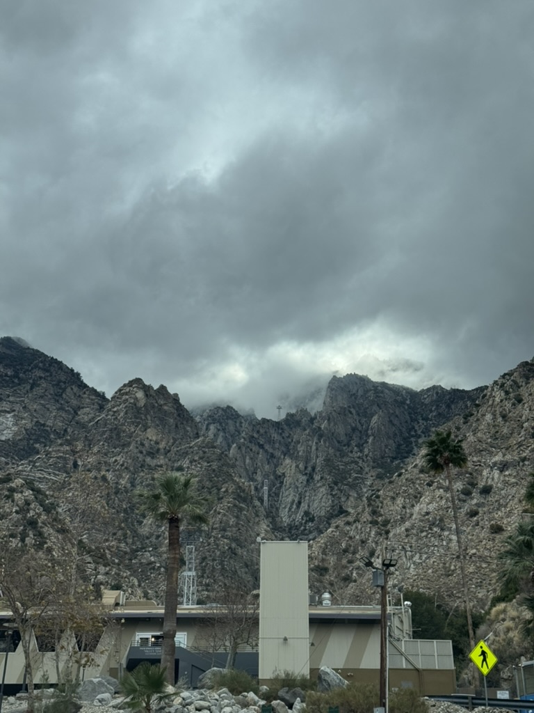 The tram base station building, cliffs and clouds rising above