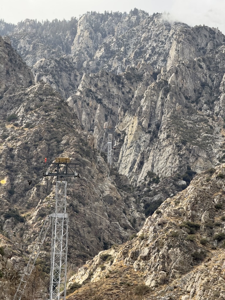 A tram car suspended on the cable above the rocky canyon
