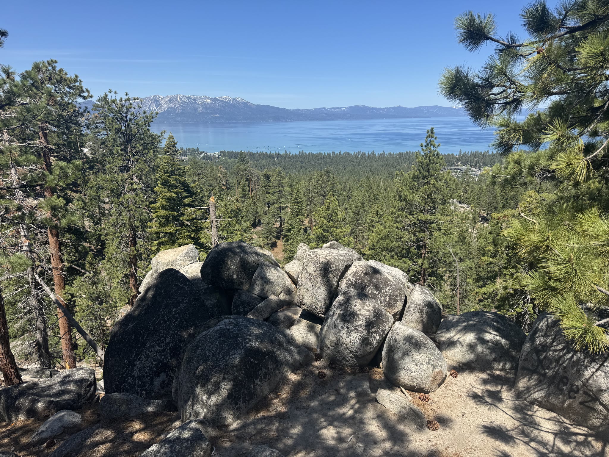 Lake viewed across a granite boulder outcrop, distant peaks in the haze