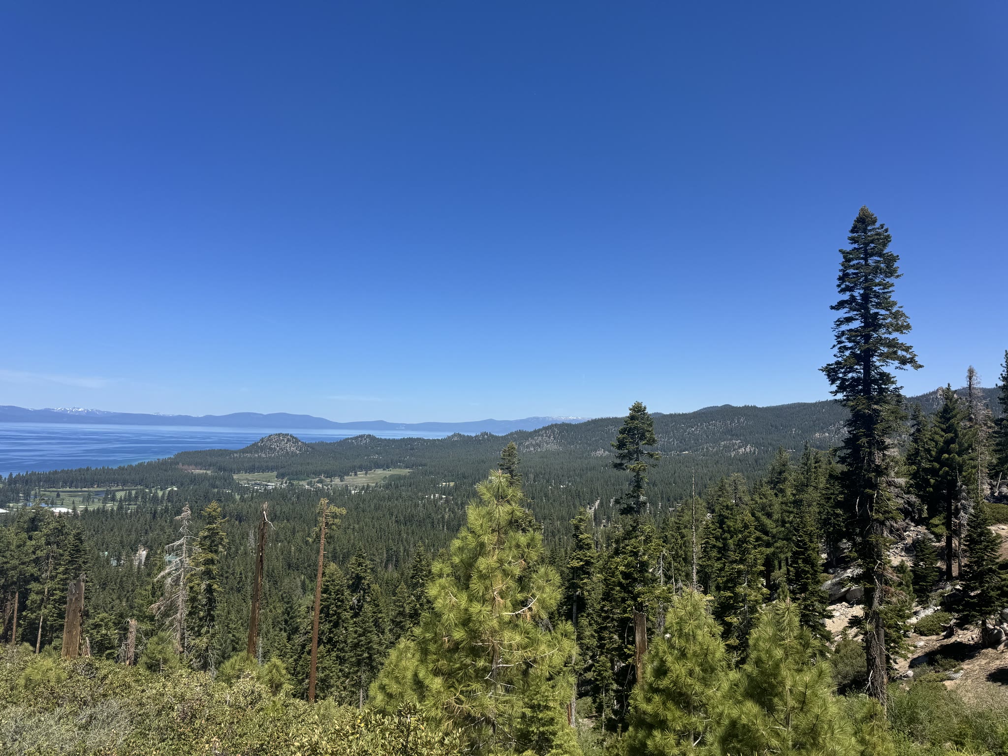 Descending switchbacks with the lake fading into haze below