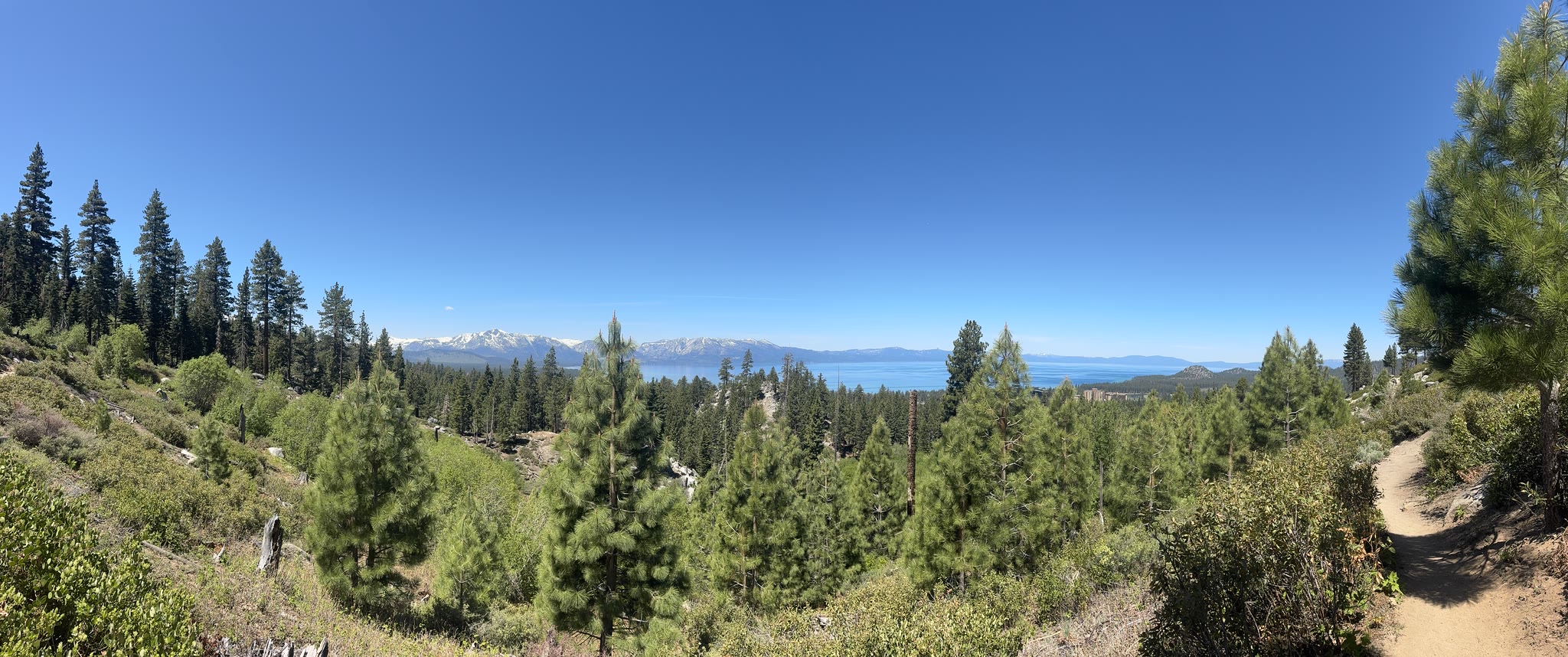 Trail vista — lake, snow-capped peaks across the water, sky above
